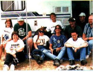 Ten people seated in front of a camper van